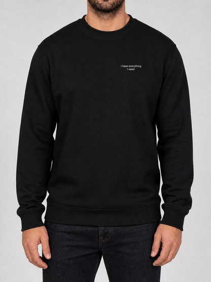 Broderie « I have everything I need. » sur le pull noir, côté cœur