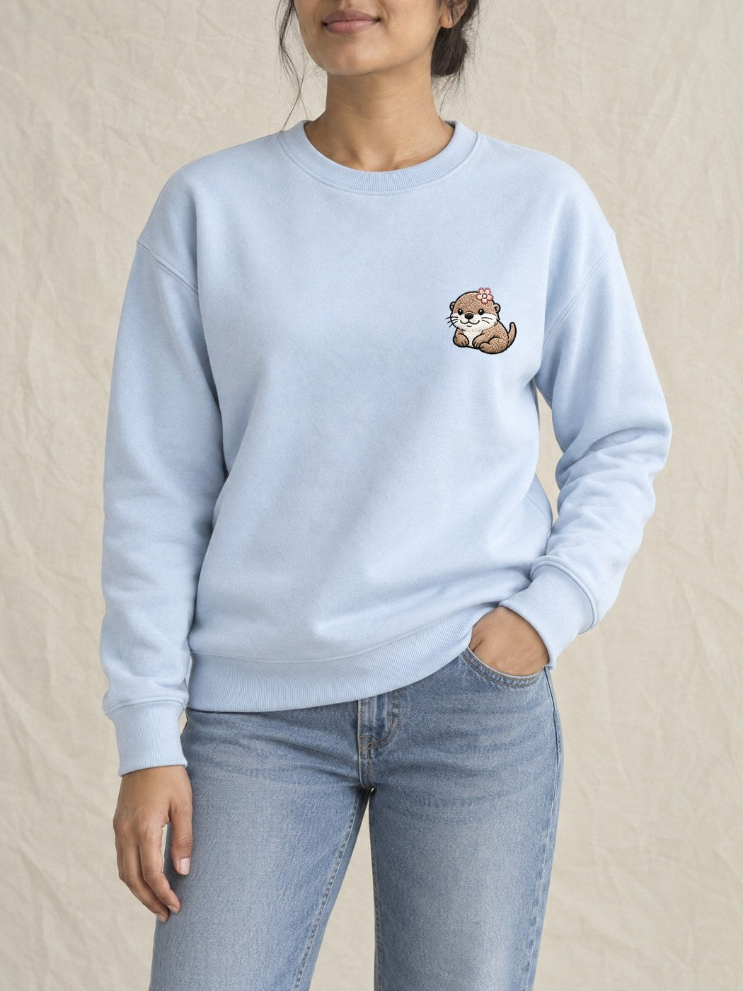 Broderie Loutre à la fleur sur le pull bleu ciel, côté cœur