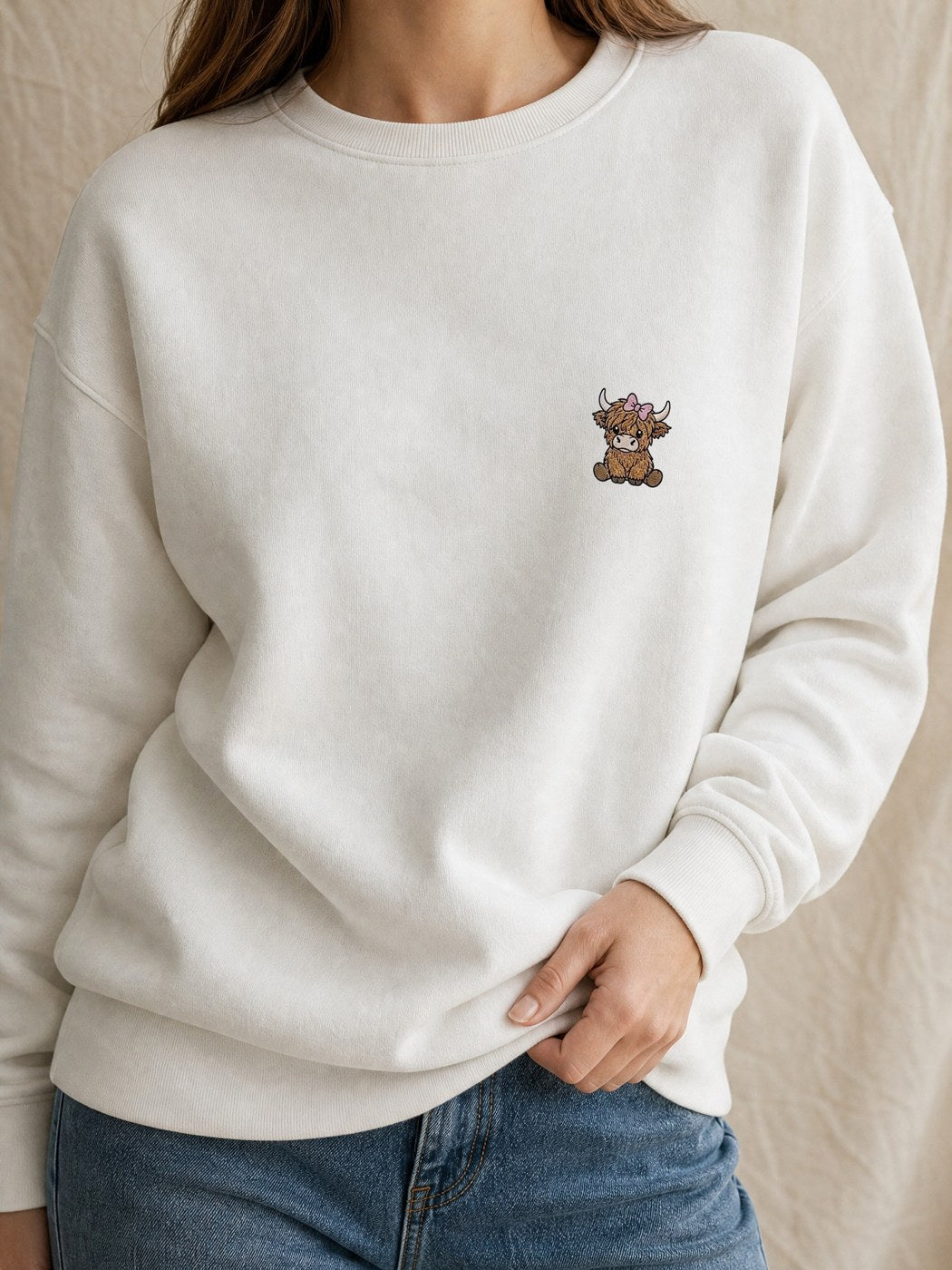 Broderie Vache highland au nœud sur le pull blanc, côté cœur